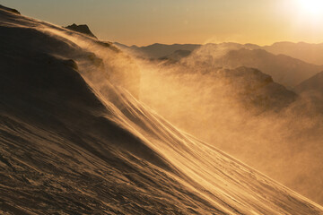 Winter sunrise high in the mountains. Weather is windy and snowy. Bright gradient colors