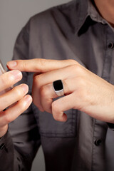 Black stone silver men's ring, ring attached to the finger of the left hand of the gray shirt male.