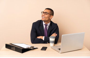 Young business man in his office with a laptop and other documents happy and smiling