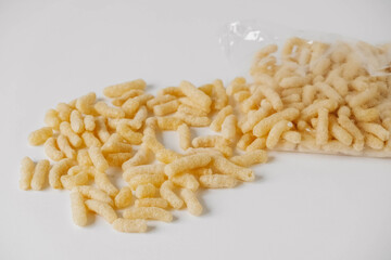 Corn sticks in a plastic bag scattered on a white background. Top view. Copy, empty space for text