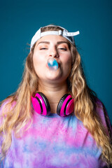 Caucasian woman blowing bubble gum playful chewing gum isolated on blue background wearing vintage 80's clothes