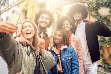 Multiethnic friends smiling and taking selfie with mobile phone.