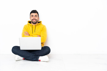 Caucasian man sitting on the floor with his laptop keeping the arms crossed in frontal position