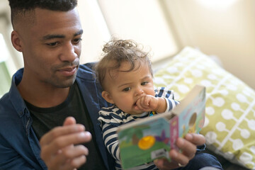 young african-american man reading book story to baby girl