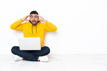 Caucasian man sitting on the floor with his laptop with surprise expression
