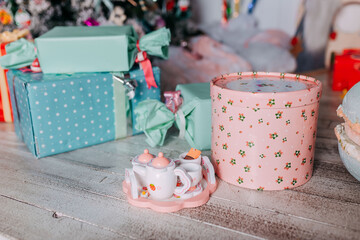 Eco-friendly christmas gifts for kids under the tree. Christmas tree decorated with toys and colorful candy canes and sweets. Present boxes under the christmas tree. Wooden toys for girls.