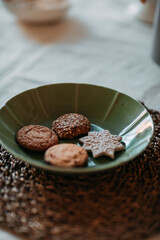 Christmas decorations. Green plate with Christmas gingerbread cookies. Decoration of festive table for christmas eve. Festive dish for new year eve.