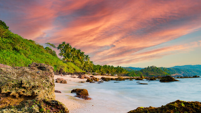 Long exposure. Beautiful and relaxing beach flanked by green palm trees at sunset. Varkala, Kerala, India.