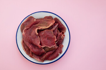 raw meat on white dish on pink background