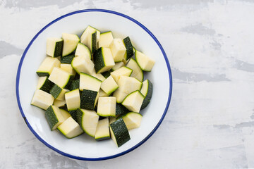 fresh courgette cut in cubes on white dish