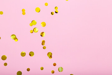 Gold confetti sparkles frame on pink background. Flat lay, top view festive backdrop with copy space. Celebration concept.