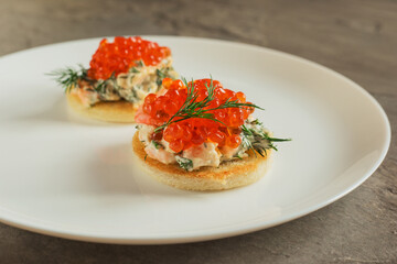 Toast skagen - classic Swedish appetizer. Sandwiches with shrimps and caviar on white plate. Selective focus.