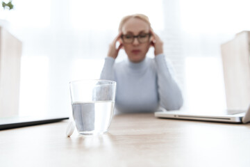 A glass of water stands on a table for sick girl.