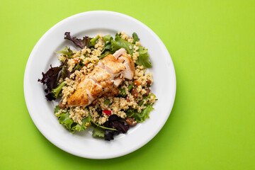 chicken with vegetables and quinoa on dish on green background