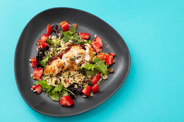 chicken with vegetables and quinoa on dish on blue background