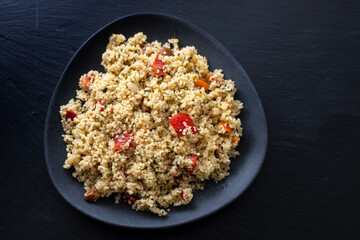 fresh vegetable salad with couscous on black plate