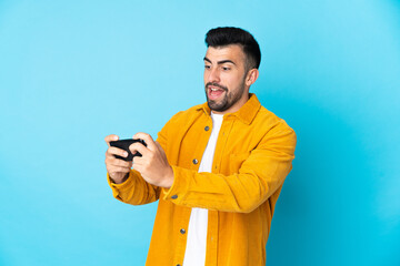 Caucasian man over isolated blue background playing with the mobile phone