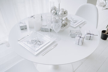 Christmas White Festival Table Decorated Gift Packages and Spherical Toys on Tray, Empty Glasses And Candles, Bow-knot on Plates, Knives and Forks Kitchen Utensil. Elegant Round Desk and Chair