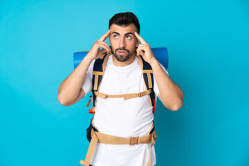 Young mountaineer man over isolated blue background having doubts and thinking