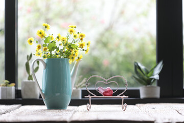 Teal tea pot with yellow Chrysanthemum inside and pink miniature heart chair 
