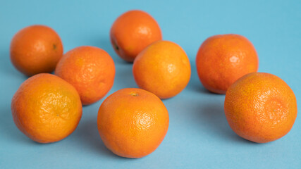 Scattered clementines, tangerines, mandarins, oranges on blue background. Winter vitamin C. Bright mood