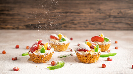 Four oatmeal baskets with banana filling and fruit on the top. Powdered sugar falls on cupcakes. Space for text