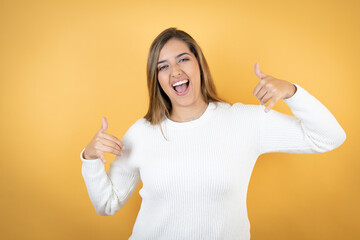 Young caucasian woman over isolated yellow background shouting with crazy expression doing rock...