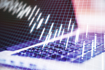 Close up of laptop on desktop with stock charts hologram