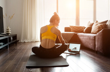 Woman doing online yoga at home. Female trener teaches asana in video conference. Health care, authenticity, sense of balance and calmness. - obrazy, fototapety, plakaty