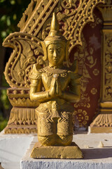 Fototapeta na wymiar Golden ancient small statue praying warrior in temple shrine Luang Pranbang Laos