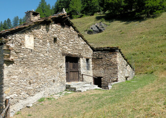 Fototapeta na wymiar A typical hut which is a simple and isolated mountain construction of the Alpine regions used as a dwelling, barn, workplace or warehouse for hay and wood 
