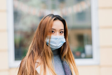 Young asian woman wearing face mask is standing at a domestic street. New normal covid-19 epidemic