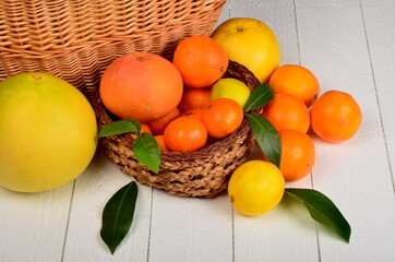 Various citrus fruits in a wicker basket on a white board