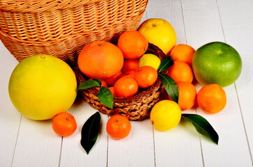 Various citrus fruits in a wicker basket on a white board