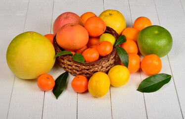 Various citrus fruits in a wicker basket on a white board