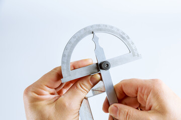 The worker measures the angle on the metal product with a digital protractor.