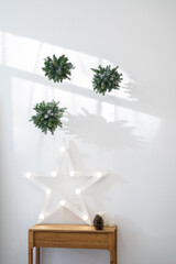 Shining star on a white wall with christmas decorations. Harsh light