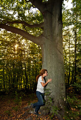 Portrait of a woman in nature. Happy woman in summer on a background of a large tree trunk and forest.