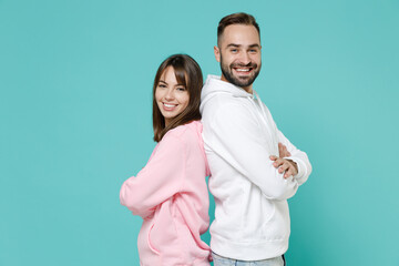 Side view of smiling young couple two friends man woman 20s in white pink casual hoodie standing...