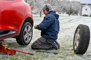 middle aged man changing tires at home