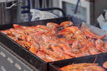 Process of cooking fresh red langoustine shrimps, prawns on grill at summer local food market - close up. Outdoor cooking, barbecue, gastronomy, seafood, cookery, street food concept
