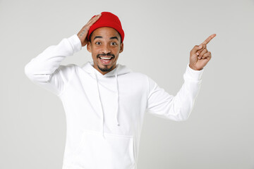 Excited young african american man 20s wearing basic casual streetwear hoodie put hand on head pointing index finger up on mock up copy space isolated on white colour background, studio portrait.