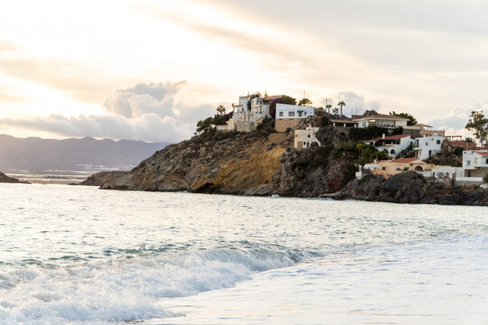 monta&ntilde;a con edificios junto al mar en el atardecer