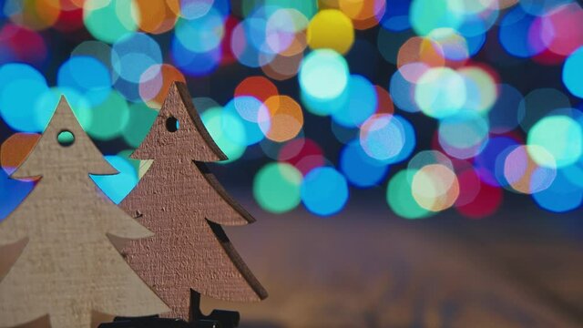 Christmas background with fir-tree wooden ornament. Twq tiny woode fir tree on bokeh backgound with place ror inscriptions.