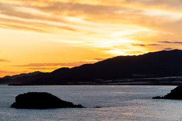 atardecer naranja contraluz junto al mar con isla