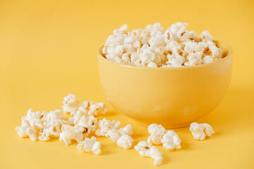 Popcorn in a yellow bowl on a yellow background. Copy, empty space for text