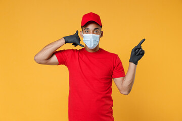Delivery employee african man in red cap blank print t-shirt face mask gloves work courier service on quarantine covid-19 concept doing phone gesture says call me back isolated on yellow background.