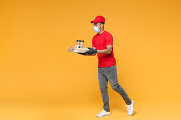 Full length delivery employee african man in red cap blank print t-shirt face mask gloves work courier service on quarantine covid-19 virus hold cardboard pizza flatbox isolated on yellow background.
