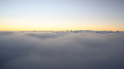 wolkenmeer mit hohen bergen im hintergrund, sonnenaufgang mit starkem nebel, helle panorama aufnahme