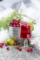 Glass of cranberry drink with berries, lime, and rosemary.